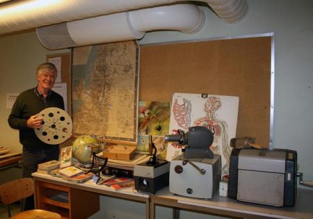 Rektor Kristen Øybekk ved Gjerstad skole poserer med en del utstyr fra tidligere tider.